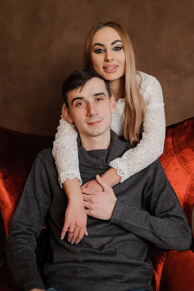 Girl hugging a guy sitting on a red chair — Stock Photo, Image