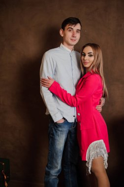 Pembe elbiseli bir kız gömlekli ve pantolonlu bir adama sarılıyor.