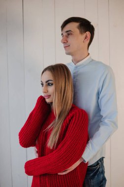 Kırmızı elbiseli bir kız pantolon ve gömlekli bir adama sarılıyor. Noel ağacı süslemeleri olan sepeti tutan bir kız.