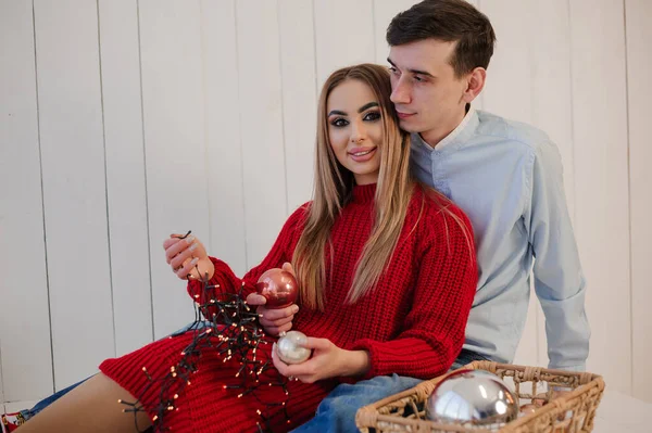 A girl in a red dress hugs a man in trousers and a shirt. Girl holding a basket with Christmas tree decorations — Stock Photo, Image