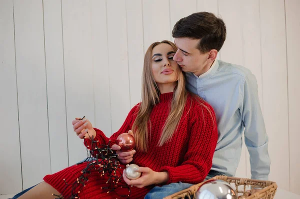 Uma menina de vestido vermelho abraça um homem de calças e camisa. Menina segurando uma cesta com decorações de árvore de Natal — Fotografia de Stock