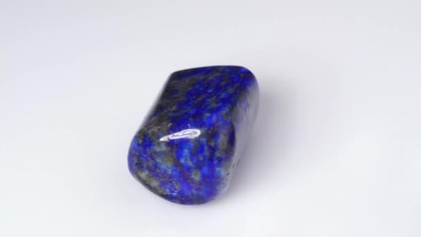 Natural blue lapis lazuli gem stone on the white background — Stock Video