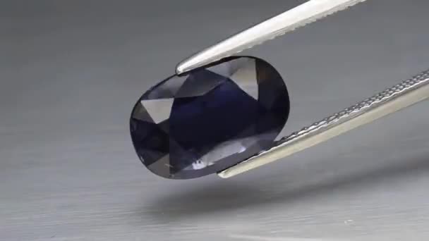 Натуральный голубой йолит драгоценный камень на поворотном столе. серый фон — стоковое видео