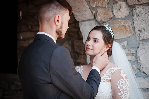 Bruden och brudgummen kramas och kysser mot bakgrund av en stenvalv. Bröllop — Stockfoto