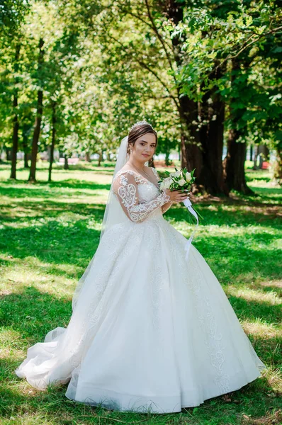 Портрет нареченої в красивій білій сукні на зеленому тлі. Наречена з букетом квітів — стокове фото