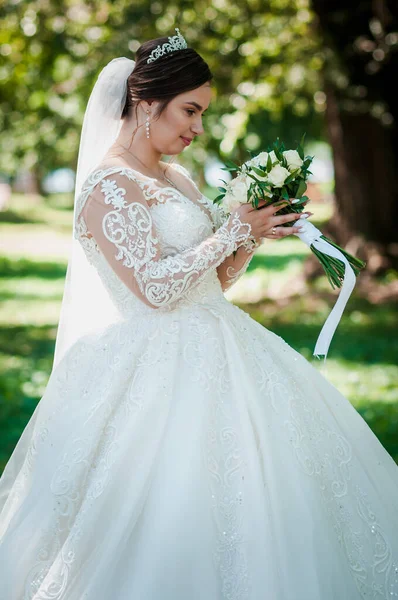 Potret pengantin wanita dengan gaun putih yang indah dengan latar belakang hijau. Pengantin dengan karangan bunga — Stok Foto