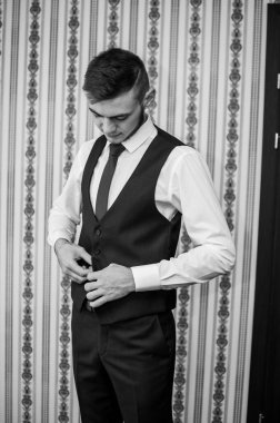 Bir adam kravatını düzeltir, ceketini ilikler, gömleğini düzeltir.