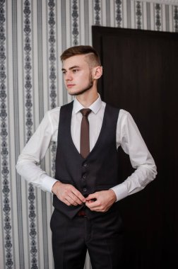 Bir adam kravatını düzeltir, ceketini ilikler, gömleğini düzeltir.