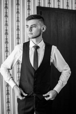 Bir adam kravatını düzeltir, ceketini ilikler, gömleğini düzeltir.