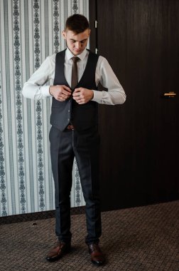 Bir adam kravatını düzeltir, ceketini ilikler, gömleğini düzeltir.