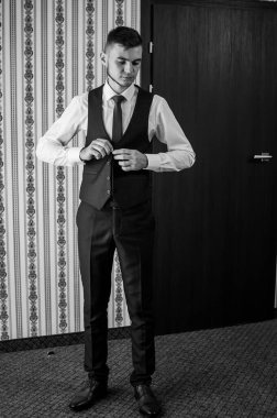 Bir adam kravatını düzeltir, ceketini ilikler, gömleğini düzeltir.