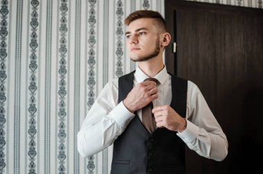Bir adam kravatını düzeltir, ceketini ilikler, gömleğini düzeltir.