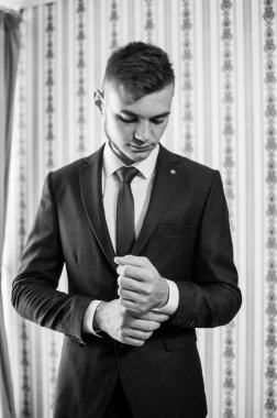 Bir adam kravatını düzeltir, ceketini ilikler, gömleğini düzeltir.