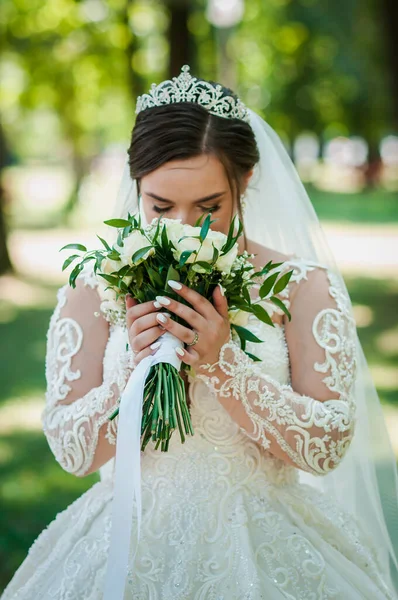 Портрет невесты в красивом белом платье на зеленом фоне. Невеста с букетом цветов — стоковое фото