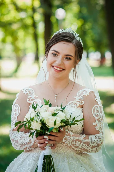 Портрет невесты в красивом белом платье на зеленом фоне. Невеста с букетом цветов — стоковое фото
