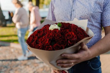 Kırmızı gül buketi, taşlı kadın altın yüzüğü. Bir buket kırmızı çiçek. Evlilik teklifi.