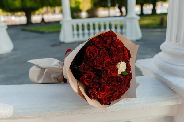 Kırmızı gül buketi, taşlı kadın altın yüzüğü. Bir buket kırmızı çiçek. Evlilik teklifi.