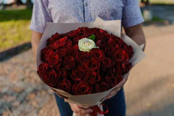 Buquê de rosas vermelhas, anel de ouro das mulheres com uma pedra. Buquê de flores vermelhas. Uma oferta de casamento — Fotografia de Stock