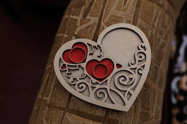 A pair of gold rings on a wooden stand in the shape of a heart — Stock Photo, Image