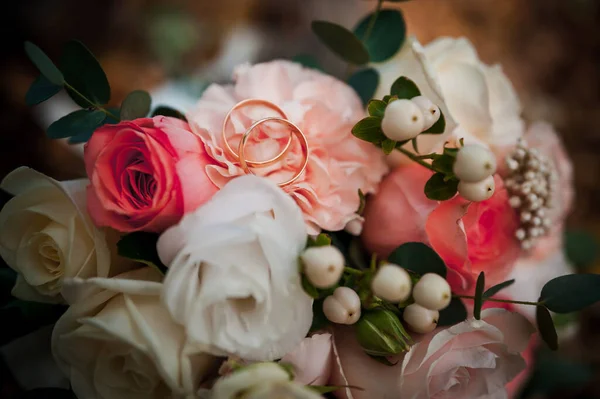 Золотые обручальные кольца, красивый свадебный букет цветов — стоковое фото