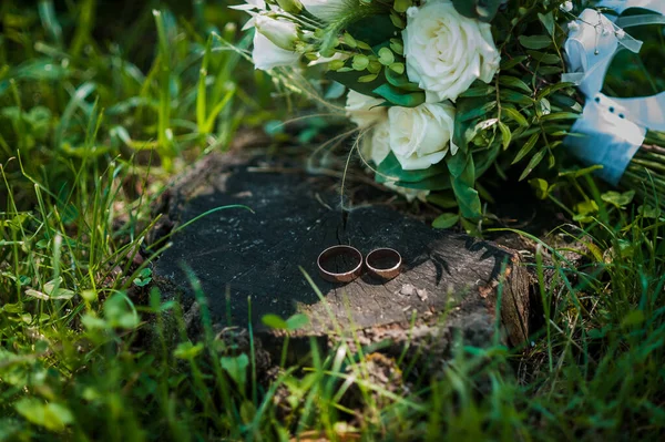 Um par de anéis de casamento dourados em um fundo de belas flores brancas — Fotografia de Stock