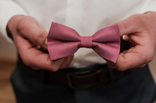 Red bow tie in the hands of the groom