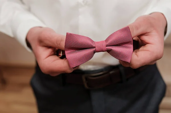 Red bow tie in the hands of the groom