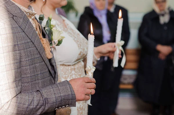 新娘和新郎在教堂举行的仪式上手持闪亮的蜡烛 教堂里的新婚夫妇手拿着蜡烛 教会的宗教细节 — 图库照片