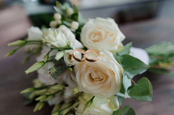 Золотые обручальные кольца на невест букет белых цветов — стоковое фото