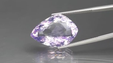 Arka plandaki cımbızla kesilmiş doğal ametist fantazisi.