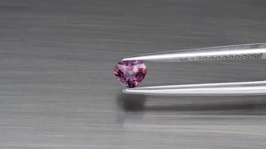 Doğal pembe kalp, cımbızda safir taşı keser.