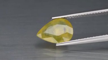 Arka plandaki cımbızda doğal sarı ateş opal taşı