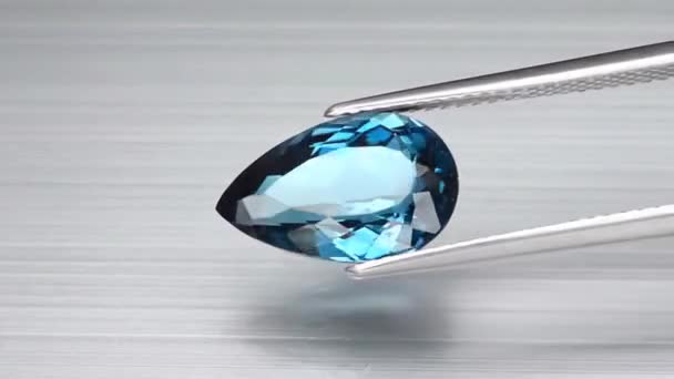 Natural london blue topaz pear cut in the turning tweezers — Stock Video