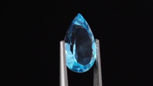 Natural blue topaz pear cut in the turning tweezers — Stock Video