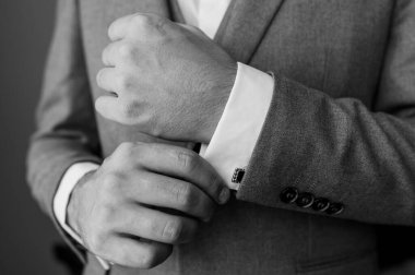 Bir damat gömleğe kol düğmesi bağlıyor.