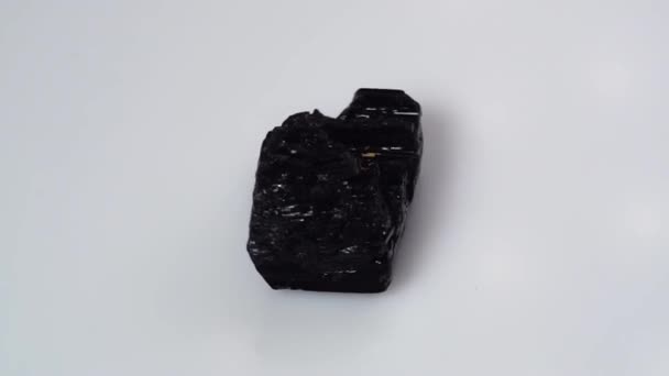 Spesimen kasar tourmaline hitam pada tabel terbalik latar belakang putih — Stok Video