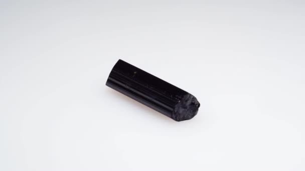 Negro turmalina scherl áspero espécimen en el fondo blanco mesa giratoria — Vídeos de Stock