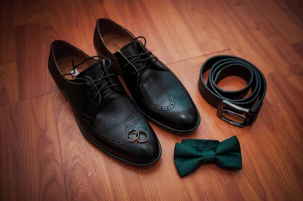 革の黒い靴 ベルト 金のリングのペア 背景に緑の蝶ネクタイ — ストック写真