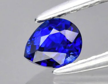 Arka planda maşalarda doğal değerli taş mavi safir.