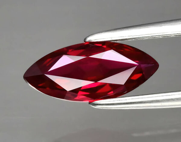 Natural gemstone red ruby in tongs on a background