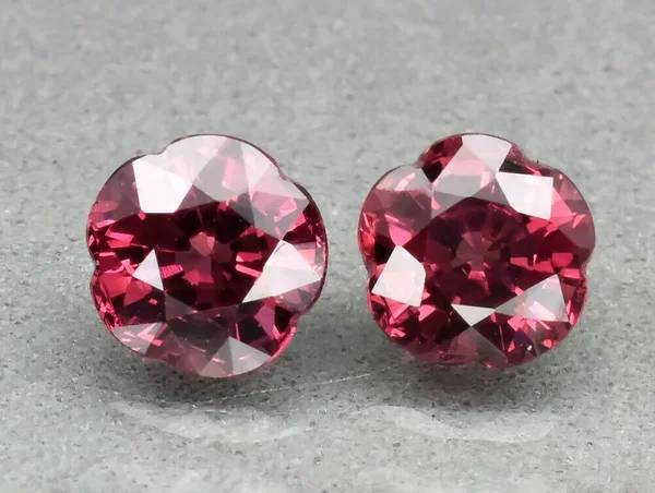 Gri bir arkaplanda cımbızla doğal değerli taş Rhodolite Garnet