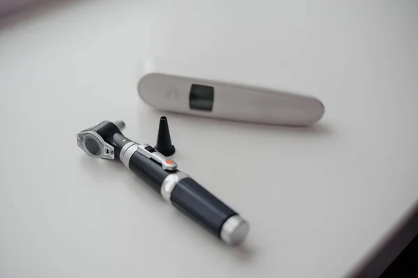 Non-contact thermometer on a white background for measuring body temperature. Otoscope on a background, a device for examining the auricle and middle ear