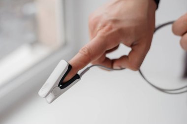 Arka planda nabız oksimetresi. Kılcal kan oksijen doygunluğunun zararsız ölçümleri için tıbbi izleme ve tanı aygıtı