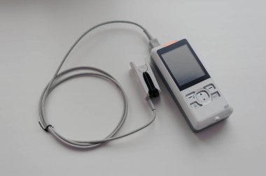 Arka planda nabız oksimetresi. Kılcal kanın oksijen ile doygunluğunu ölçmek için tıbbi kontrol ve tanı aygıtı