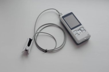 Arka planda nabız oksimetresi. Kılcal kanın oksijen ile doygunluğunu ölçmek için tıbbi kontrol ve tanı aygıtı