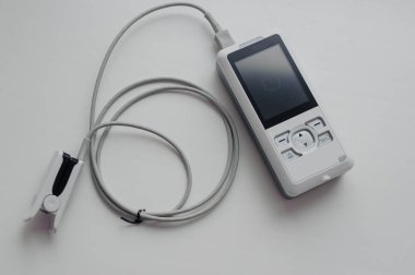 Arka planda nabız oksimetresi. Kılcal kanın oksijen ile doygunluğunu ölçmek için tıbbi kontrol ve tanı aygıtı