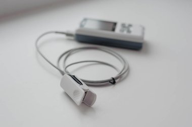 Arka planda nabız oksimetresi. Kılcal kanın oksijen ile doygunluğunu ölçmek için tıbbi kontrol ve tanı aygıtı