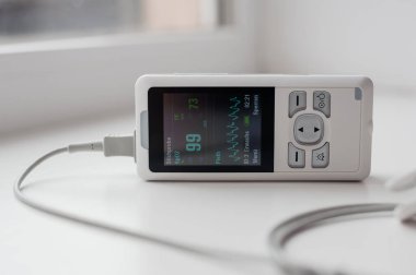 Parmak nabız oksimetresi kullanan bir adam, sağlık izleme konsepti. Arka planda nabız oksimetresi