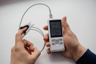 Parmak nabız oksimetresi kullanan bir adam, sağlık izleme konsepti. Arka planda nabız oksimetresi