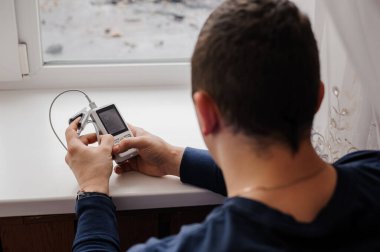 Parmak nabız oksimetresi kullanan bir adam, sağlık izleme konsepti. Beyaz arkaplanda nabız oksimetresi